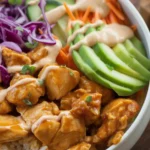 Delicious Bang Bang Chicken Bowl with seasoned chicken, creamy sauce, rice, and fresh vegetables.