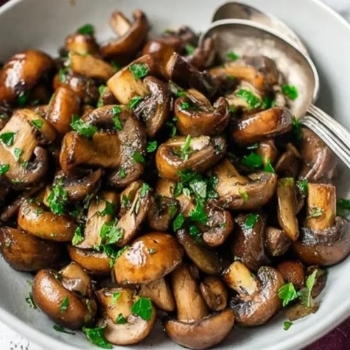 Close-up of a bowl of perfectly cooked, glossy Garlic Butter Mushrooms garnished with fresh parsley.