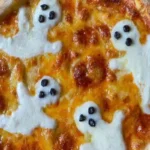 Halloween PIZZA GHOSTS topped with melted mozzarella ghosts with black-olive eyes on a golden, bubbly cheese crust.