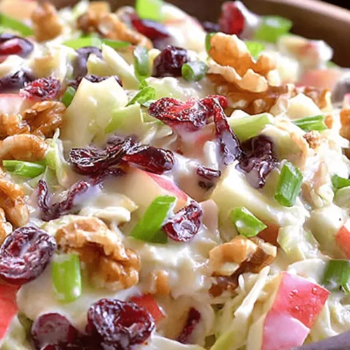 Vibrant Apple Cranberry Coleslaw in a rustic wooden bowl, featuring crisp apples, tart cranberries, crunchy walnuts, and green onions in a creamy dressing.