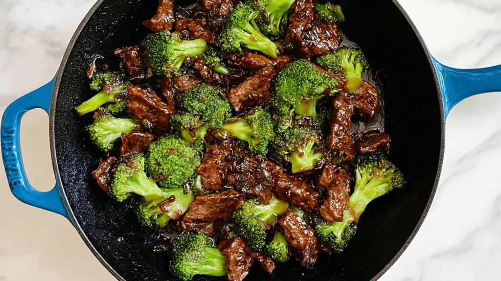 Delicious beef and broccoli recipe stir-fry in a vibrant blue cast iron skillet, ready to serve.