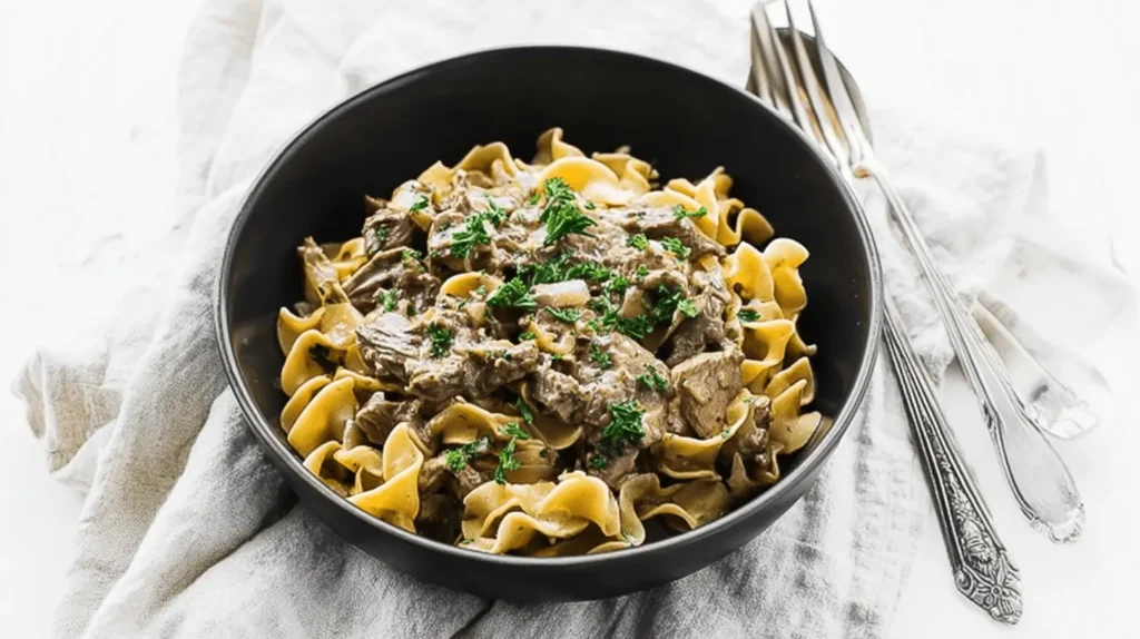 A beautifully plated bowl of creamy beef stroganoff with tender beef and egg noodles, garnished with fresh parsley, perfect for a classic beef stroganoff recipe.