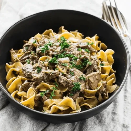 A beautifully plated bowl of creamy beef stroganoff with tender beef and egg noodles, garnished with fresh parsley, perfect for a classic beef stroganoff recipe.