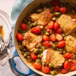 Rustic chicken thigh recipe served in a Dutch oven and on a plate with tomatoes and olives.