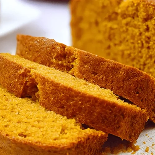 Freshly baked, moist slices of easy pumpkin bread recipe on a rustic white board.