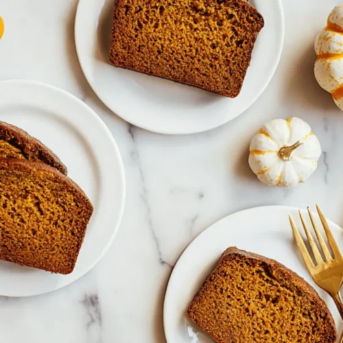 Overhead shot of moist slices of healthy pumpkin bread with decorative gourds on a white marble surface.