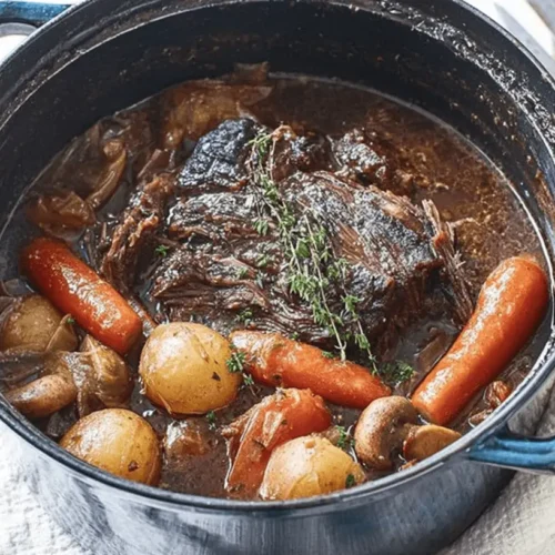 Close-up of a hearty pot roast recipe with tender beef, carrots, and potatoes in a STAUB Dutch oven.