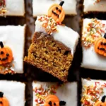 Overhead view of festive pumpkin bars topped with creamy frosting, autumn sprinkles, and adorable jack-o'-lantern candy pumpkins.