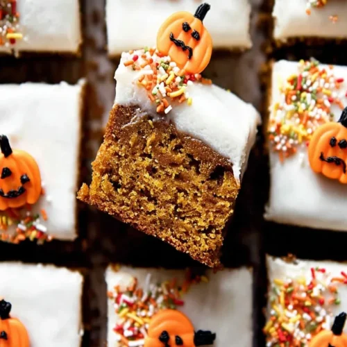 Overhead view of festive pumpkin bars topped with creamy frosting, autumn sprinkles, and adorable jack-o'-lantern candy pumpkins.