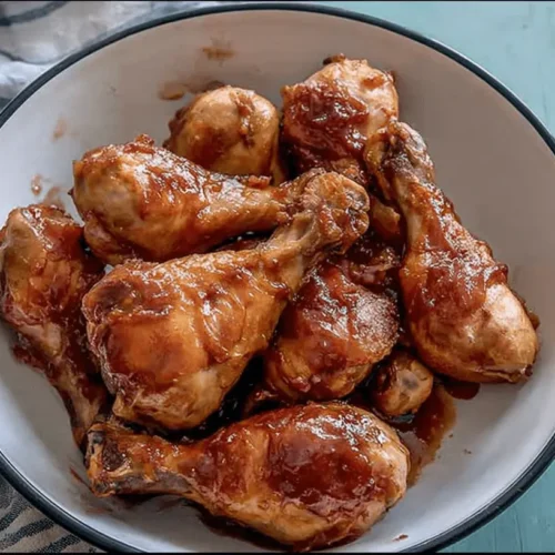 Appetizing close-up of glazed Slow Cooker Drumsticks (4-Ingredients!) served in a rustic white bowl.