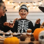 Joyful family celebrating Halloween, eating Spooky Skeleton Cupcakes, with a boy in a skeleton costume and festive decorations.