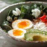 Close-up of a vibrant Savory Breakfast Bowl with Parmesan, featuring soft-boiled eggs, avocado, red bell pepper, and greens in a rustic bowl.