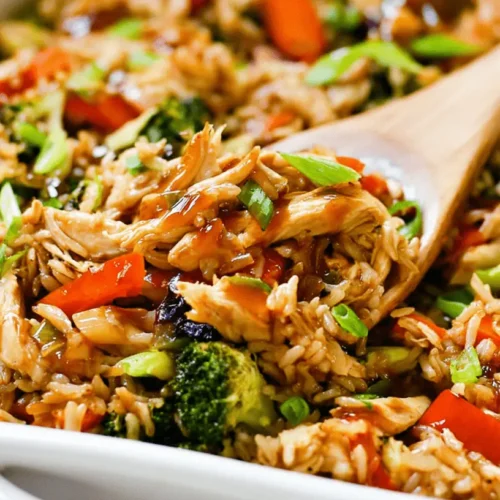 Close-up of a Teriyaki Chicken Casserole with chicken, vegetables, and rice being served from a white dish.