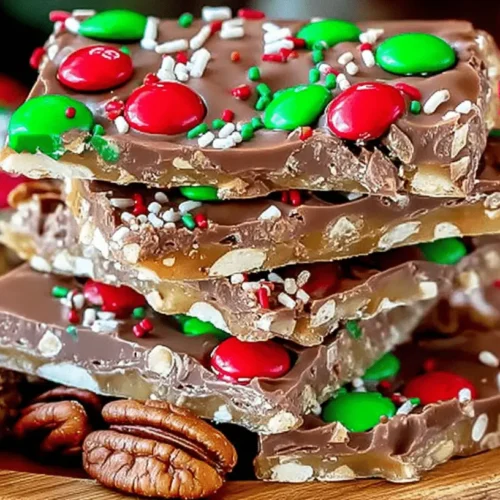 A festive stack of homemade chocolate toffee bark, often called Christmas Crack, adorned with red and green holiday candies and sprinkles, perfect for a Christmas Crack Recipe.