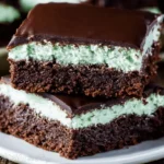 Close-up of perfectly layered Mint Chocolate Brownies with a rich chocolate base, vibrant mint filling, and glossy chocolate glaze.