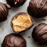 A top-down view of delicious chocolate-covered Peanut Butter Balls (Truffles), some decorated with sprinkles, with one cut open to reveal the creamy filling.