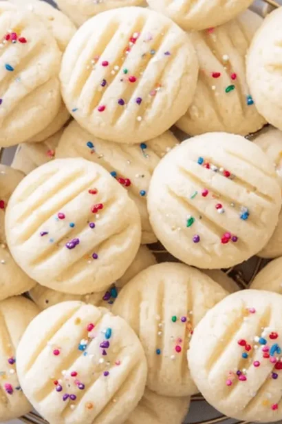 Overhead view of a gold basket filled with festive rainbow-sprinkled Whipped Shortbread Cookies and Christmas ornaments.