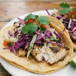 Delicious grilled fish tacos topped with fresh slaw served on a plate